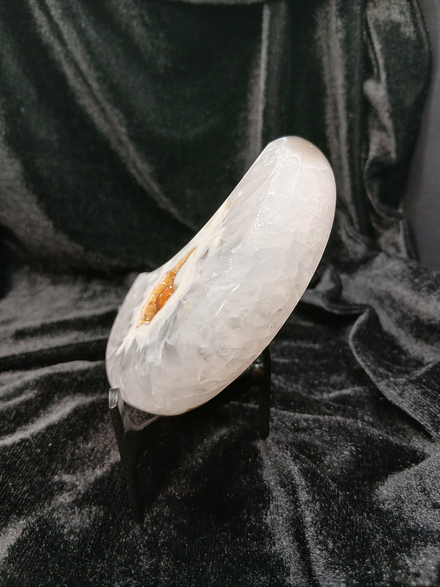 Fordite Haus: Crystals & Fordite agate moon carving with a central druzy geode pocket on a black display stand.