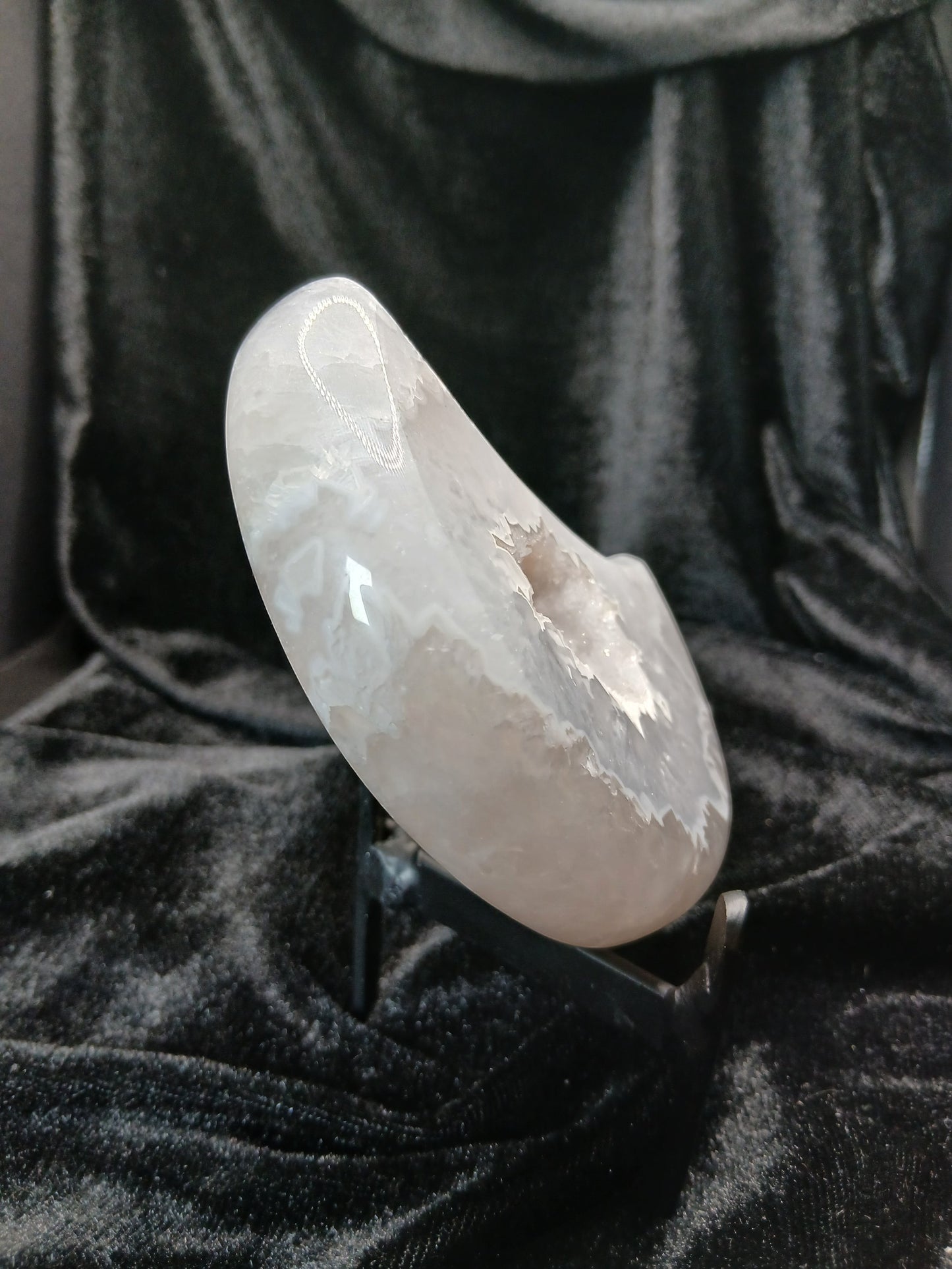 Fordite Haus: Crystals & Fordite agate moon carving with a sparkling druzy center displayed on a black metal stand.