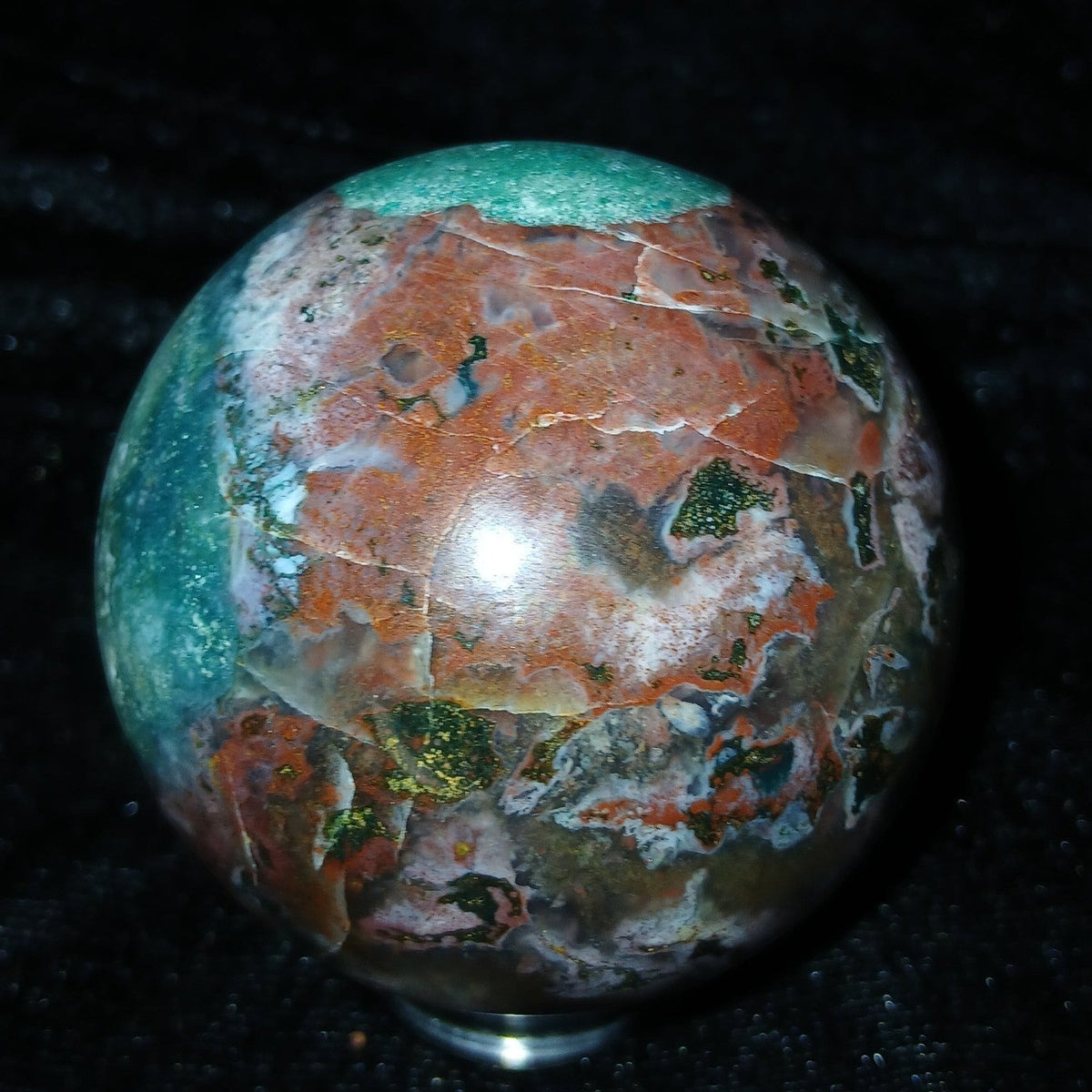 Fordite Haus: Crystals & Fordite 57.3mm Ocean Jasper sphere with polished greenish-blue, red, and white patterns.