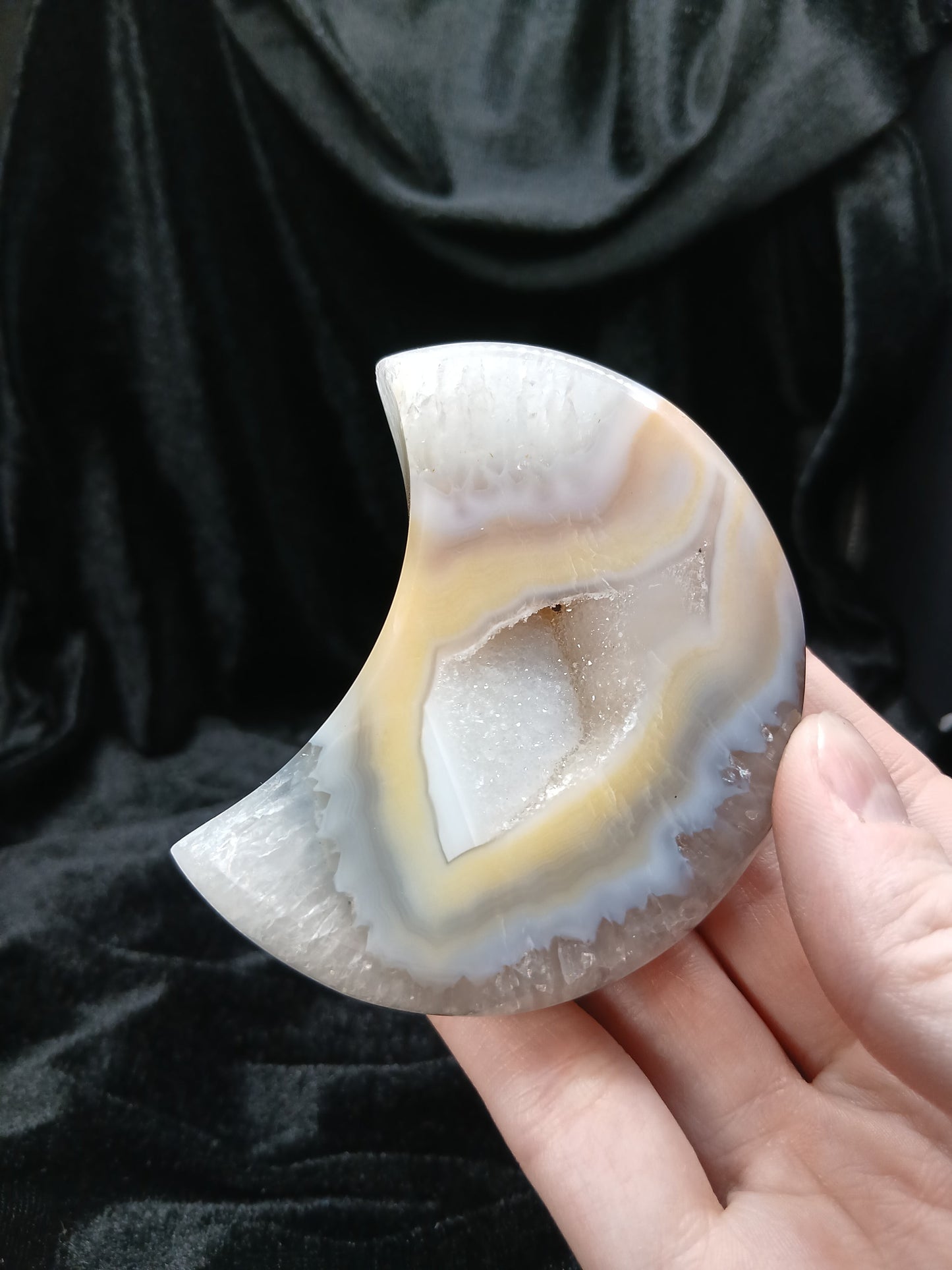 Fordite Haus: Crystals & Fordite peachy agate moon carving with natural cream banding and a central druzy geode center.