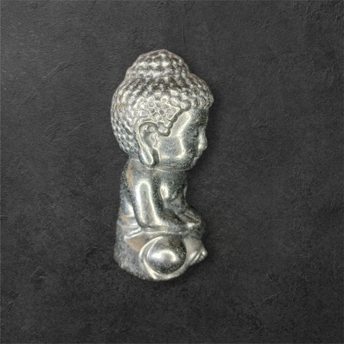 Fordite Haus: Crystals & Fordite small metallic silver meditating Buddha figurine in a seated pose.