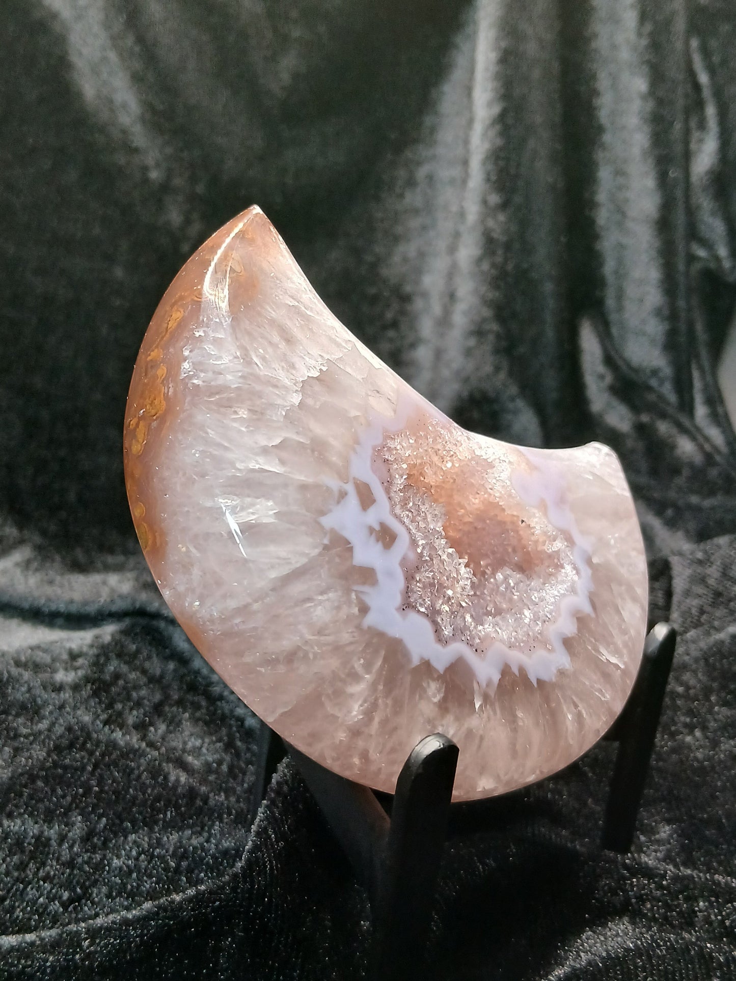 Fordite Haus: Crystals & Fordite agate druzy moon carving with sparkling crystal center on a black display stand.