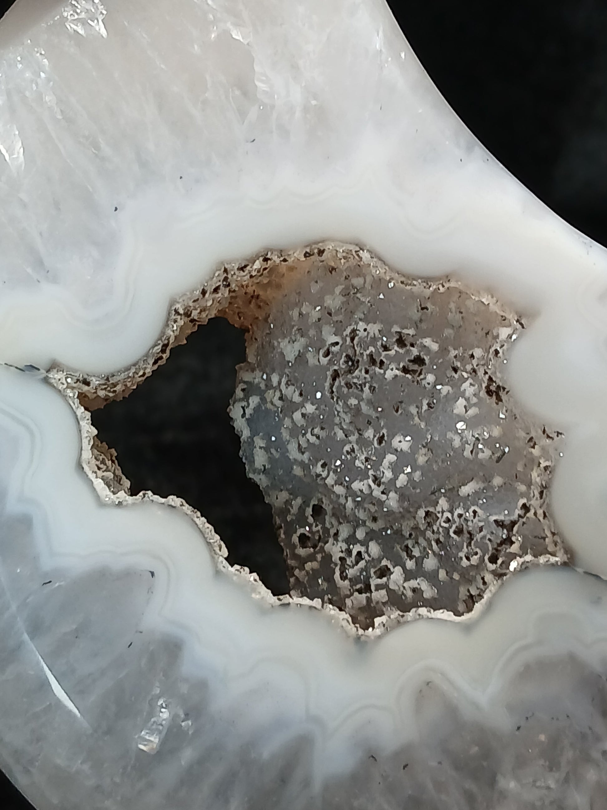 Fordite Haus: Crystals & Fordite agate moon carving featuring a sparkling grey druzy center and white banded edges.