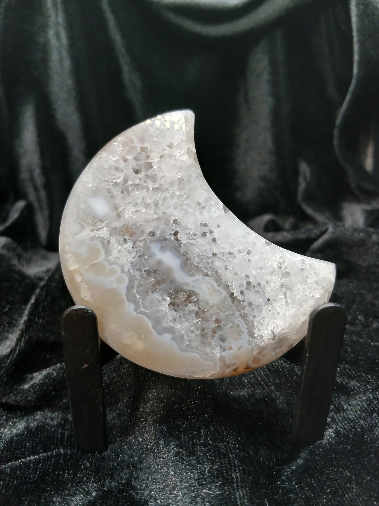 Fordite Haus: Crystals & Fordite agate moon carving with icy white and blue banding, druzy caves, and display stand.