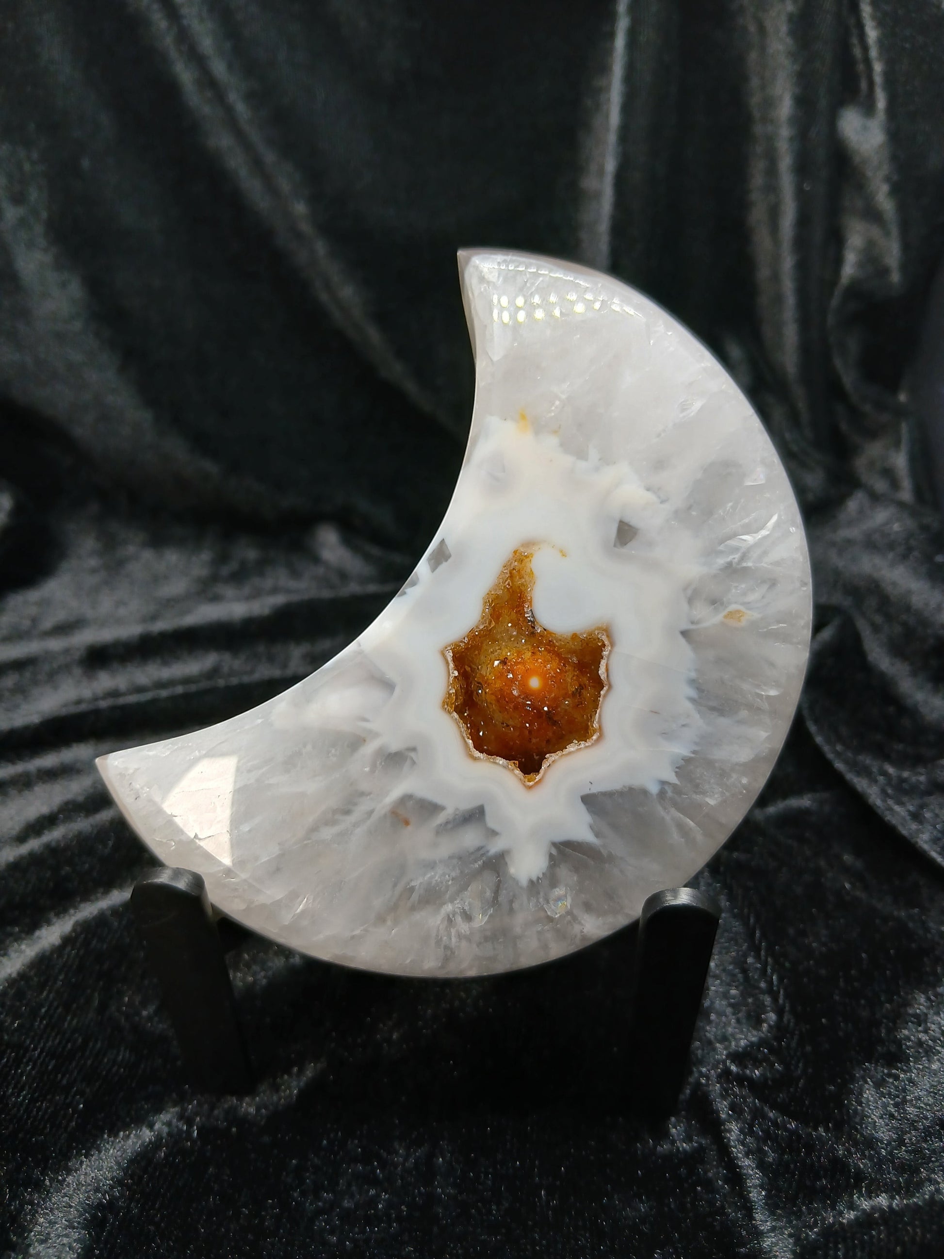 Fordite Haus: Crystals & Fordite agate moon carving with a central druzy geode pocket on a black display stand