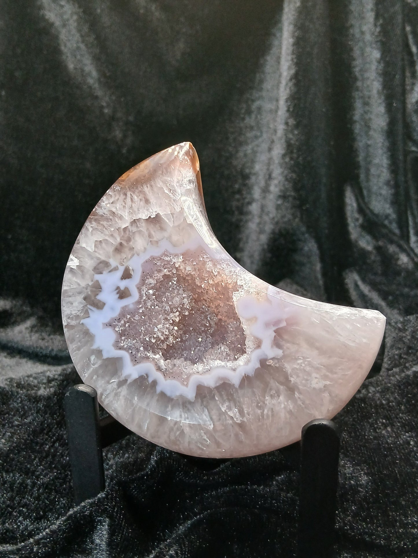 Fordite Haus: Crystals & Fordite 3.5-inch agate moon carving with a sparkling druzy center on a black display stand.