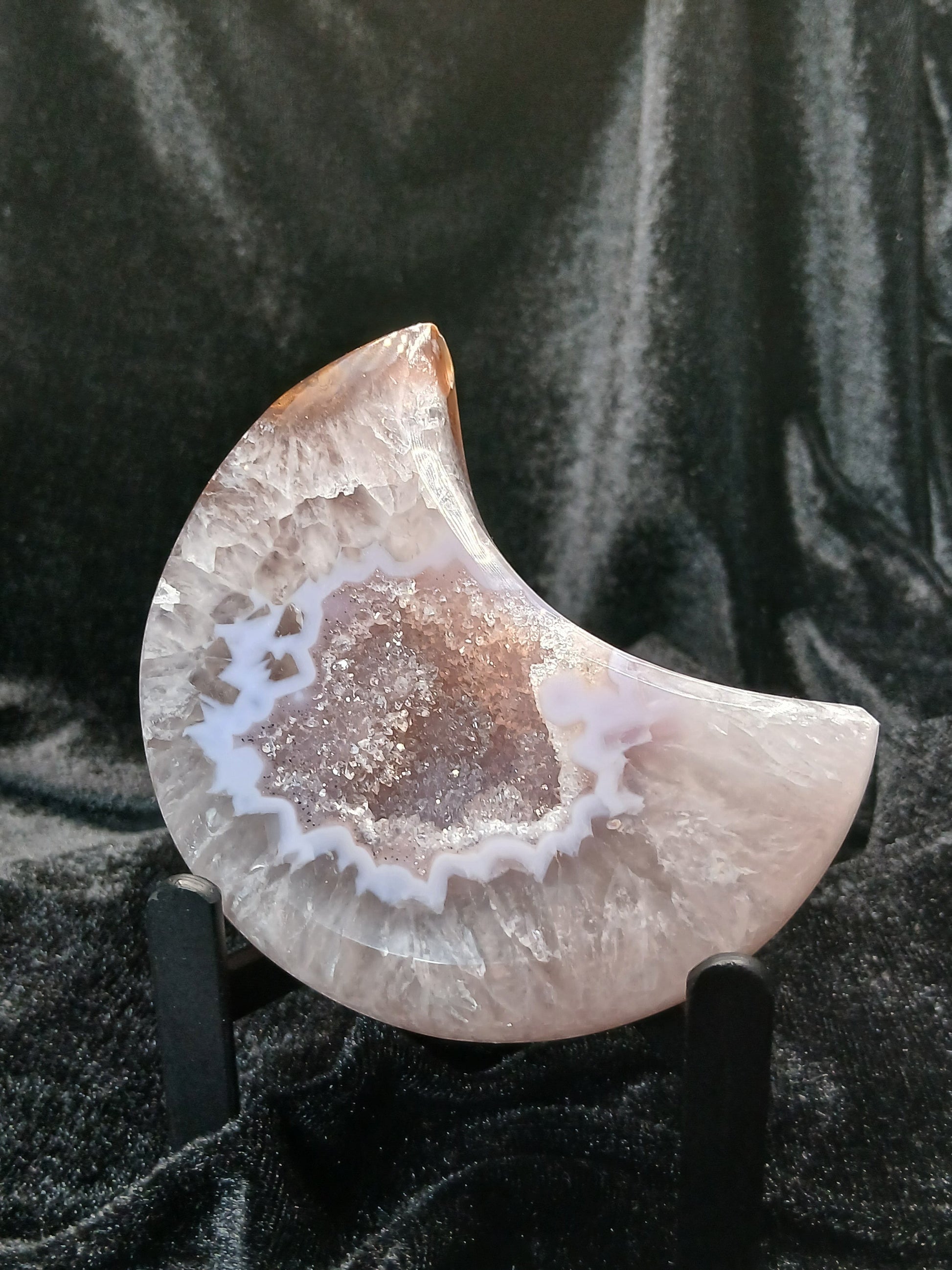 Fordite Haus: Crystals & Fordite 3.5-inch agate moon carving with a sparkling druzy center on a black display stand.
