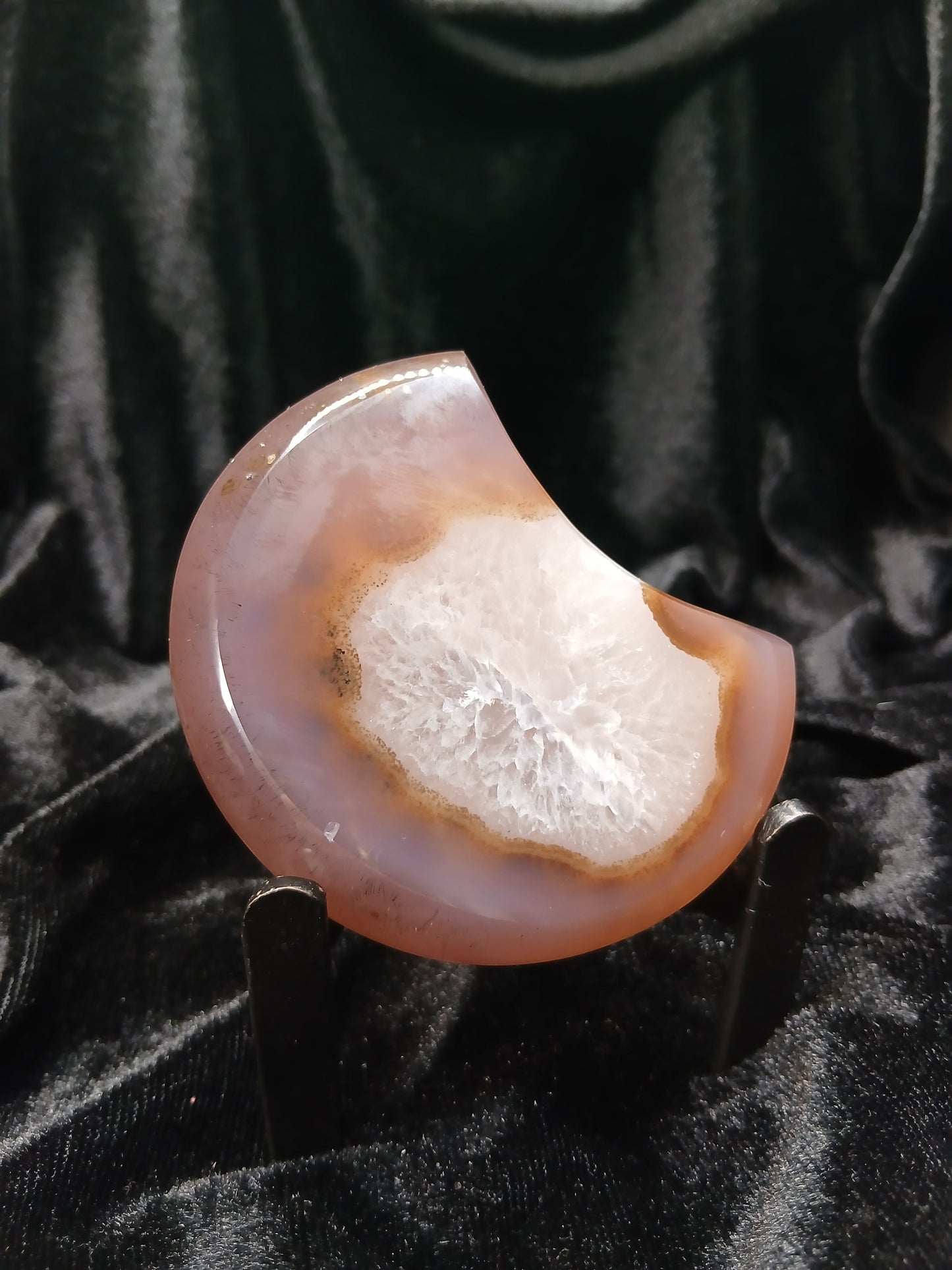 Fordite Haus: Crystals & Fordite taupe and white agate moon carving with a central druzy geode on a display stand.
