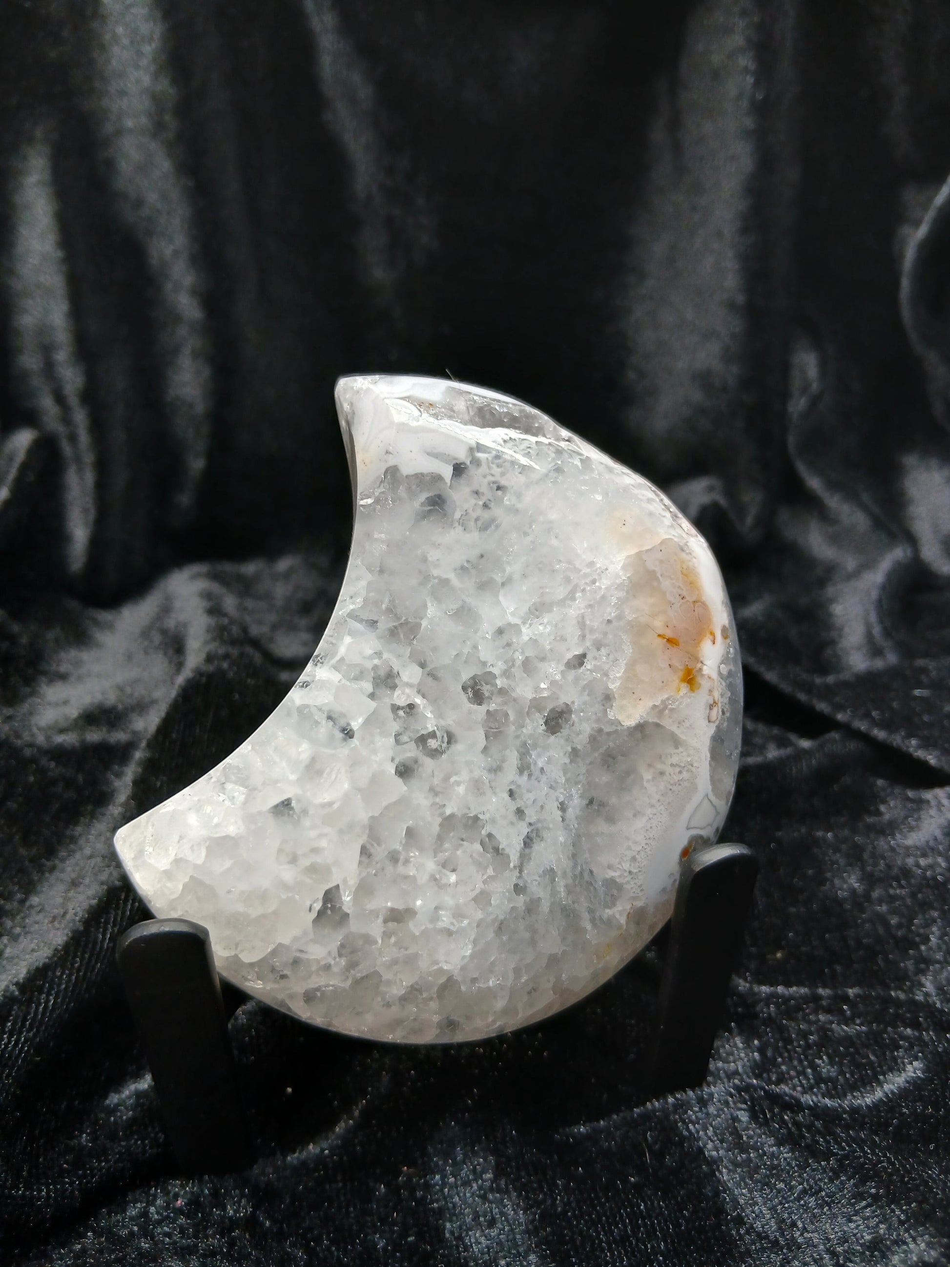 Fordite Haus: Crystals & Fordite 3-inch agate moon carving with a crystalline center on a black display stand