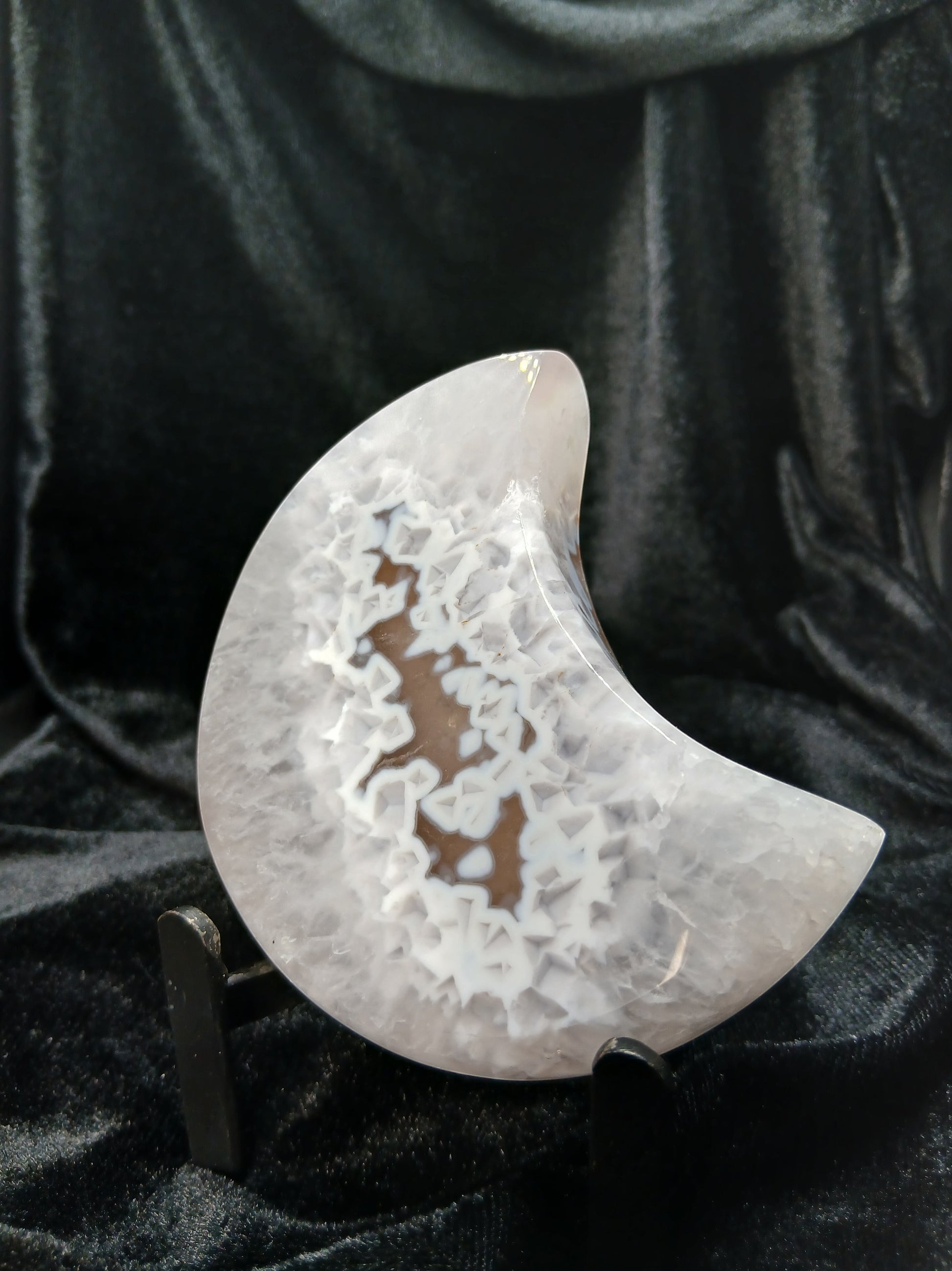 Fordite Haus: Crystals & Fordite agate moon carving with intricate white crystalline patterns on a black stand.