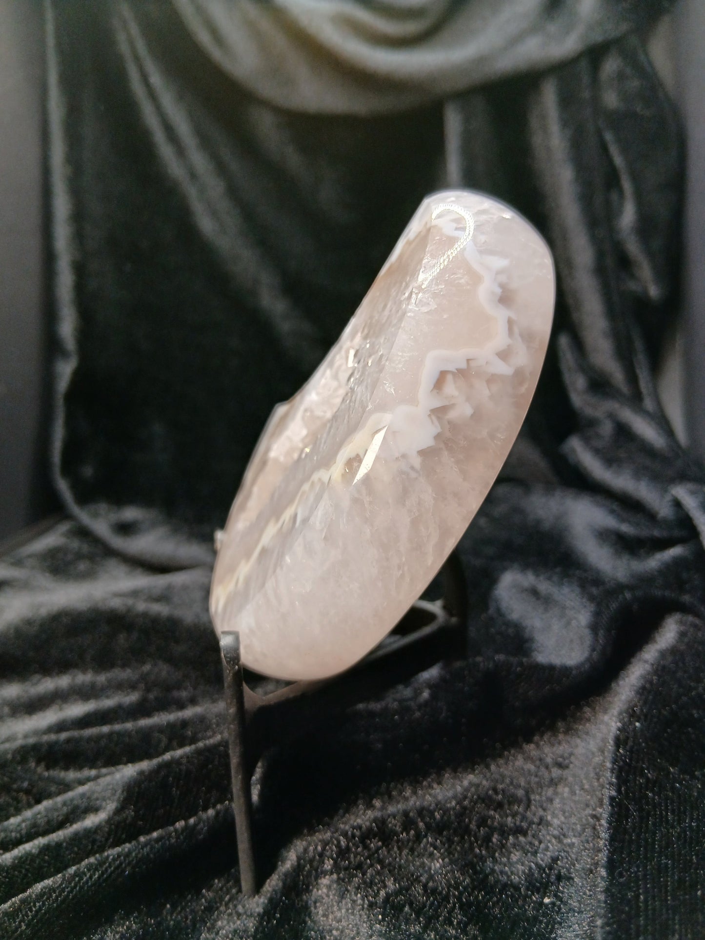 Fordite Haus: Crystals & Fordite agate moon carving with white crystalline patterns on a black velvet display stand