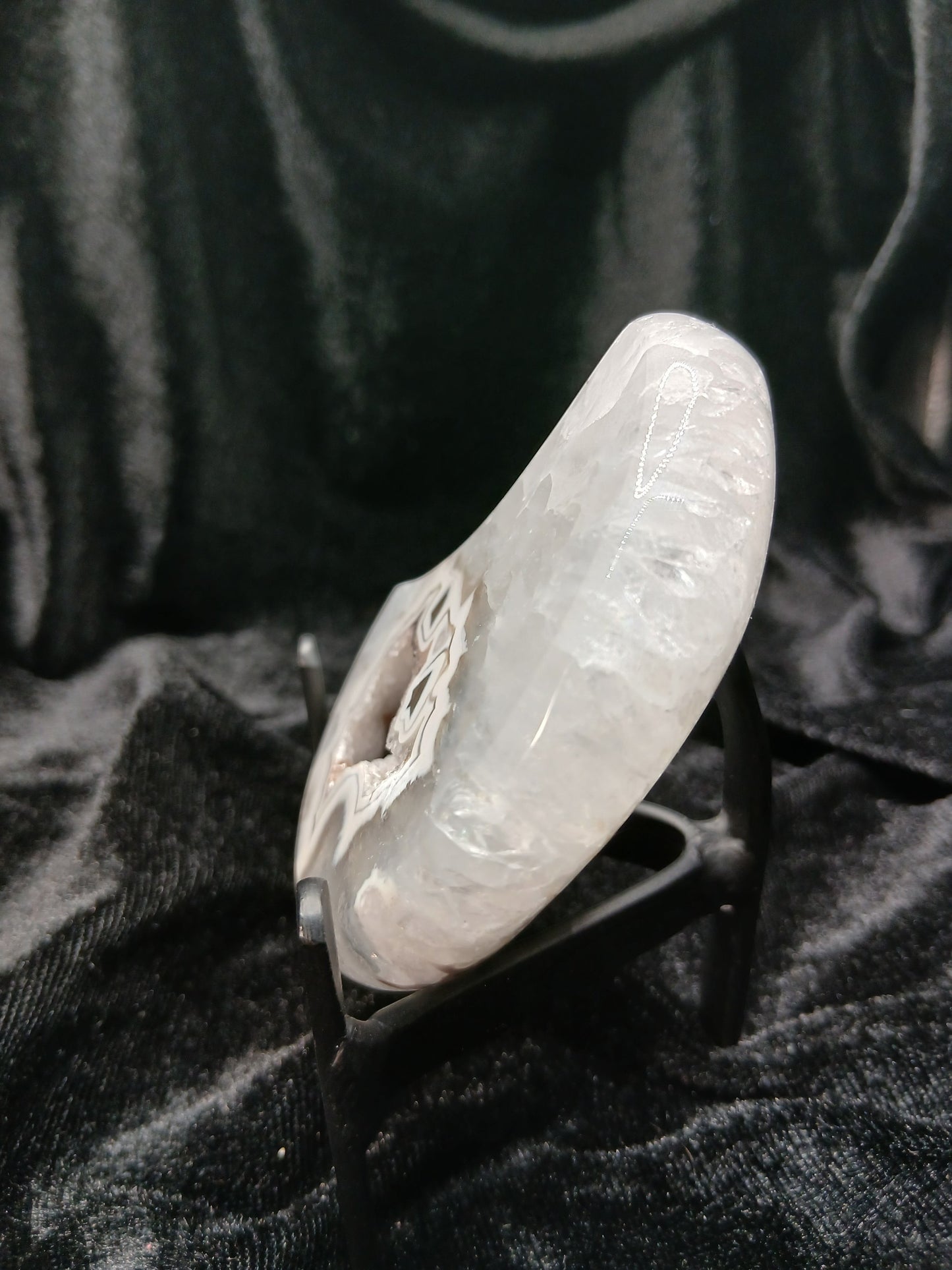 Fordite Haus: Crystals & Fordite 3-inch agate moon carving with crystalline texture on a black display stand
