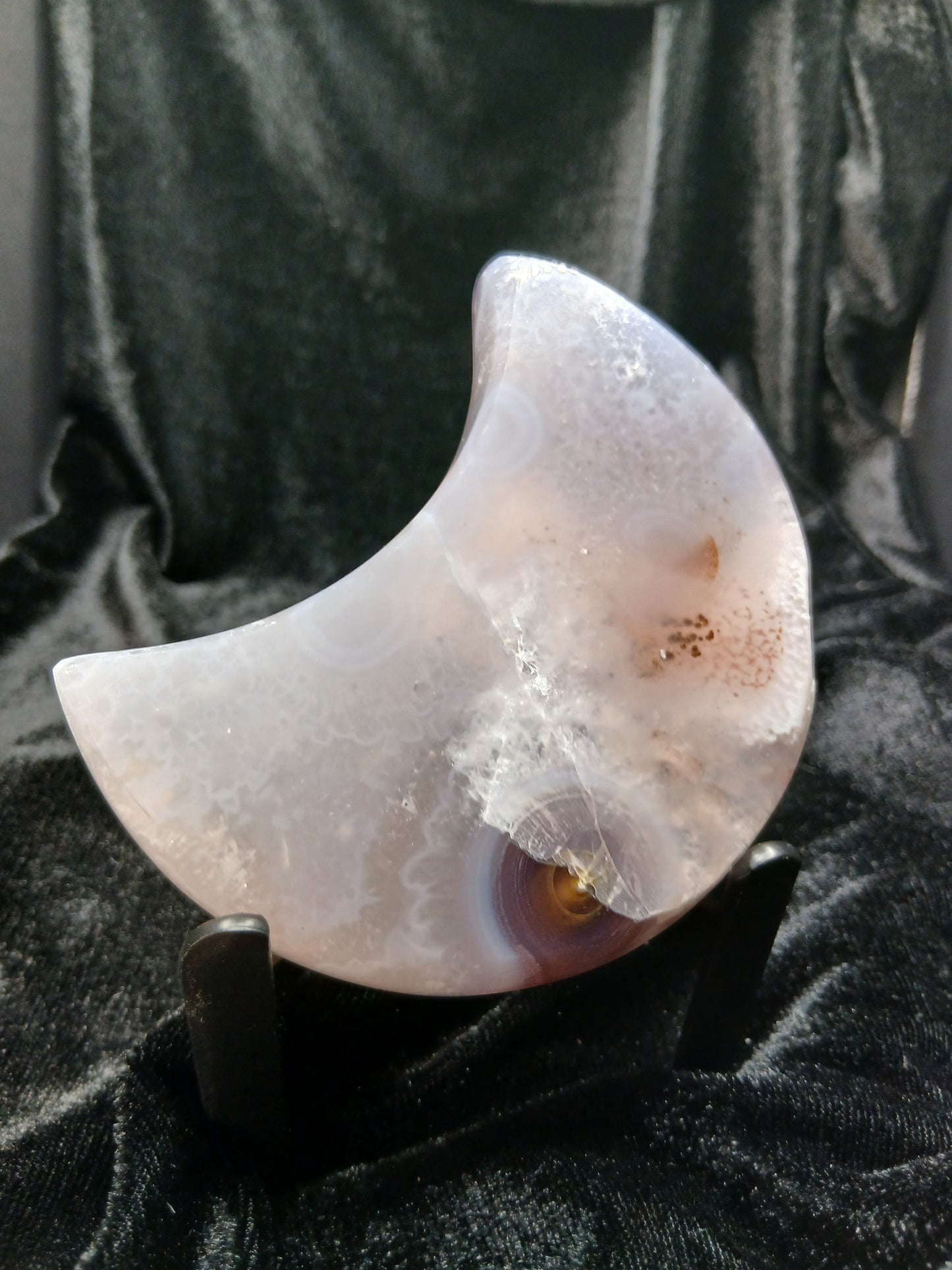 Fordite Haus: Crystals & Fordite agate moon carving with translucent banding and natural inclusions on a black stand