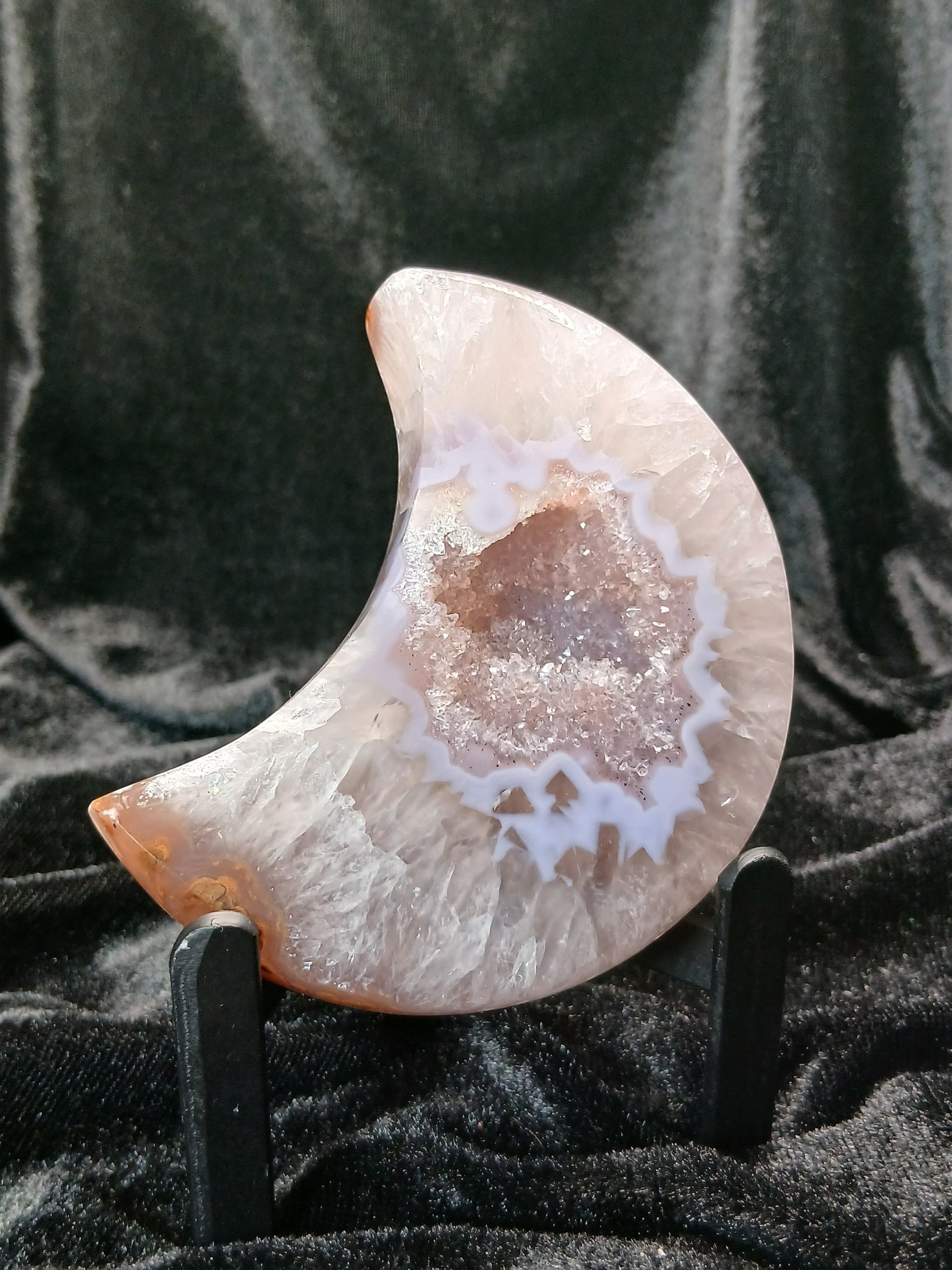 Fordite Haus: Crystals & Fordite 3.5-inch agate moon carving with a sparkling druzy center on a black display stand.