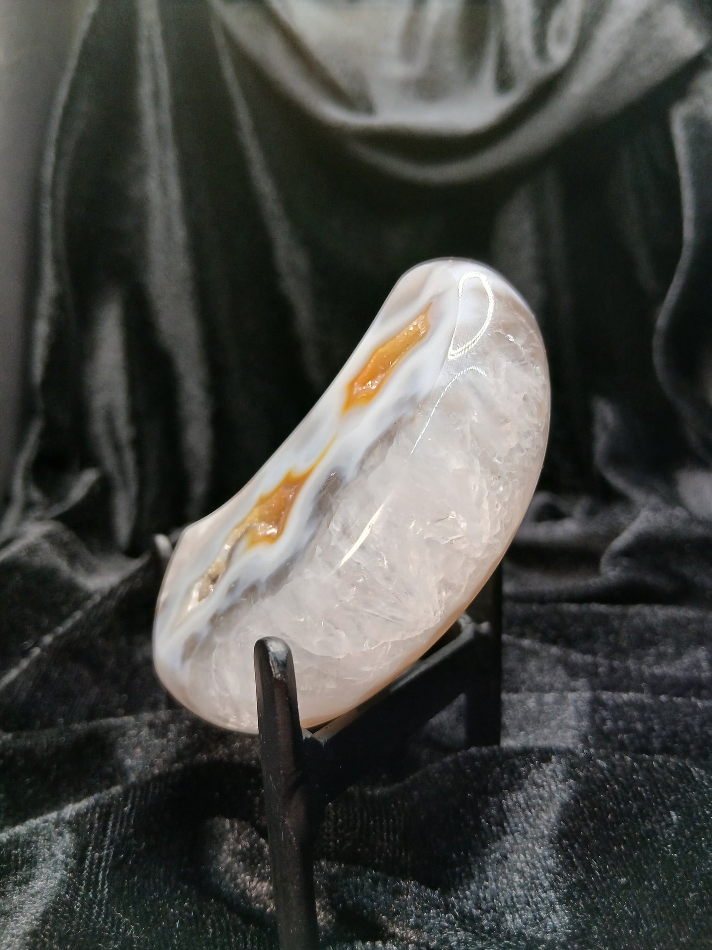Fordite Haus: Crystals & Fordite agate moon carving with icy white, blue, and amber druzy details on a display stand