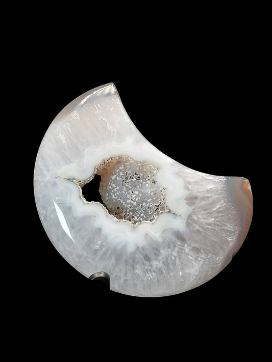 Fordite Haus: Crystals & Fordite agate moon carving with a central druzy geode cavity on a black display stand.