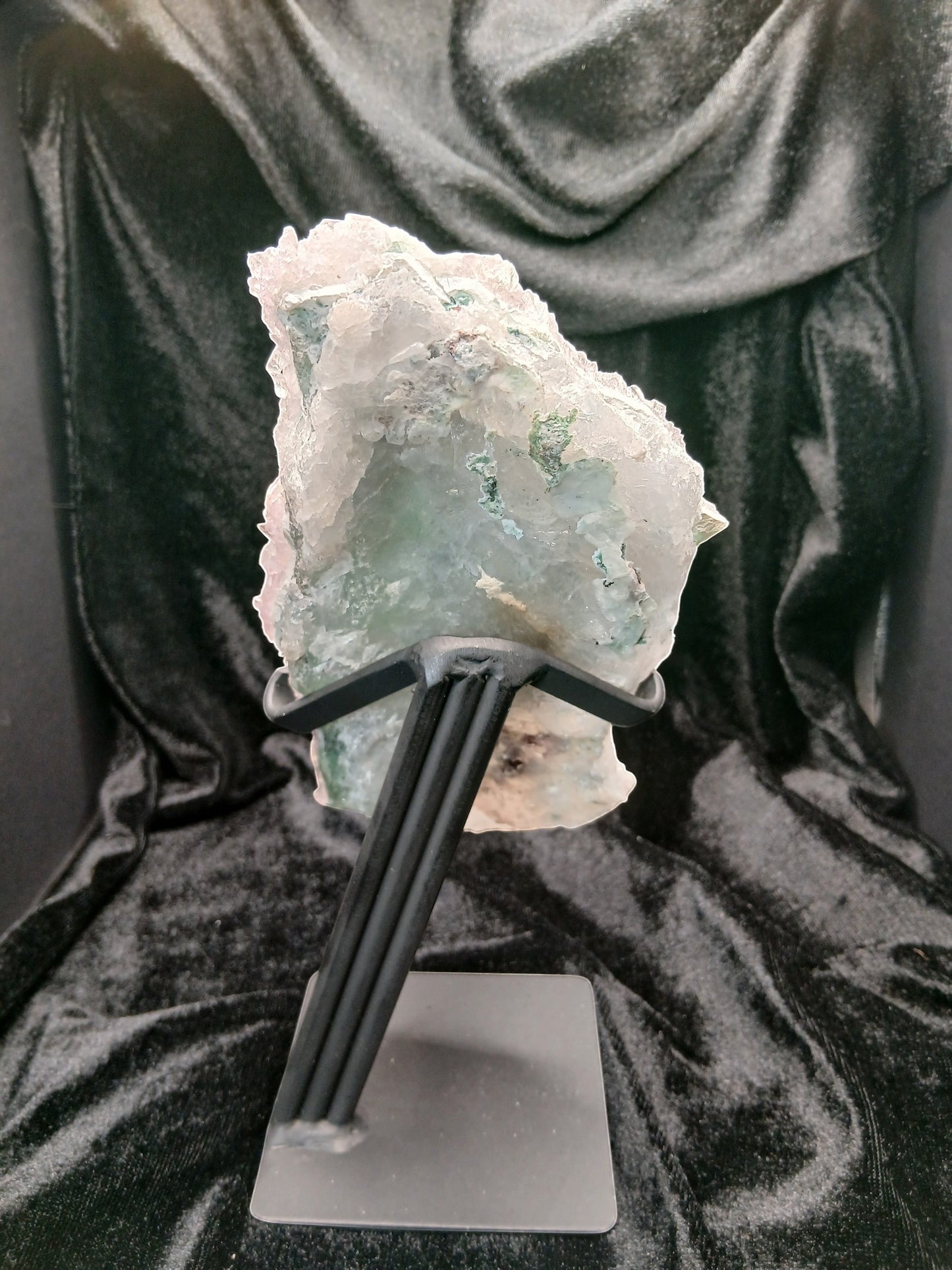 Fordite Haus: Crystals & Fordite green chalcedony and lavender amethyst flower crystal specimen on a black metal stand.