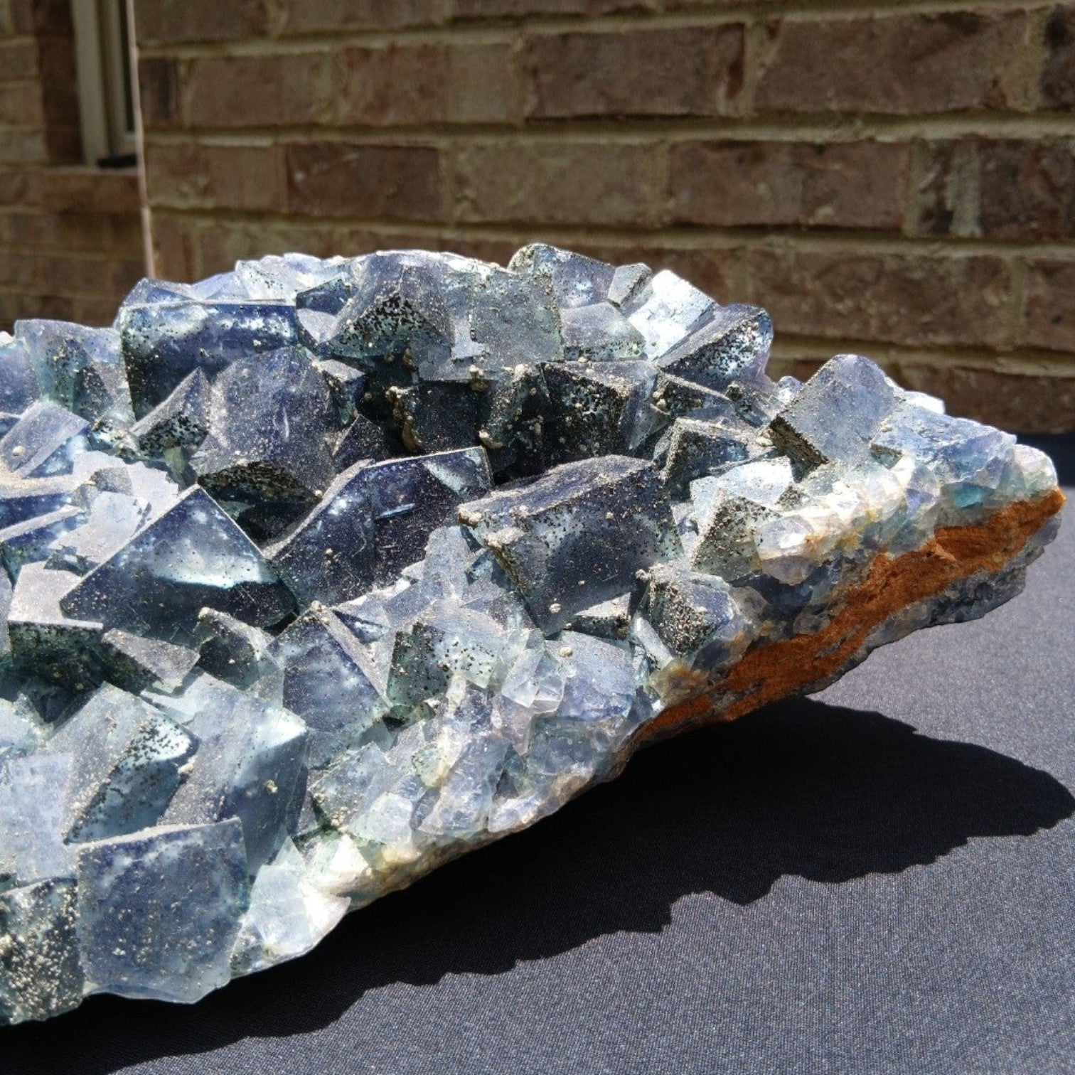 Fordite Haus: Crystals & Fordite green Superior Mine fluorite mineral specimen with pyrite dusting on a dark surface.