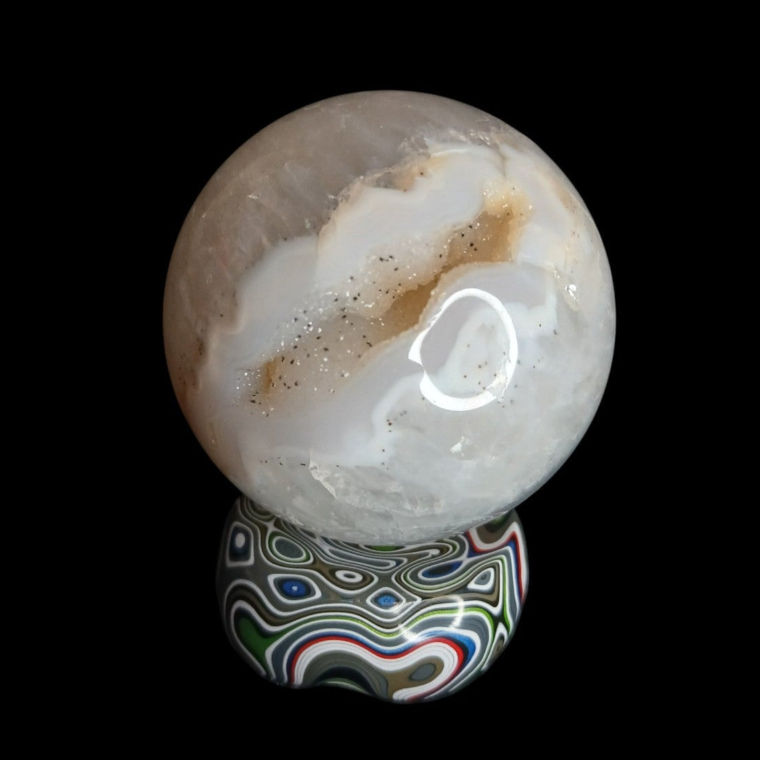 Fordite Haus: Crystals & Fordite Jeepite sphere stand featuring colorful layered automotive paint patterns.