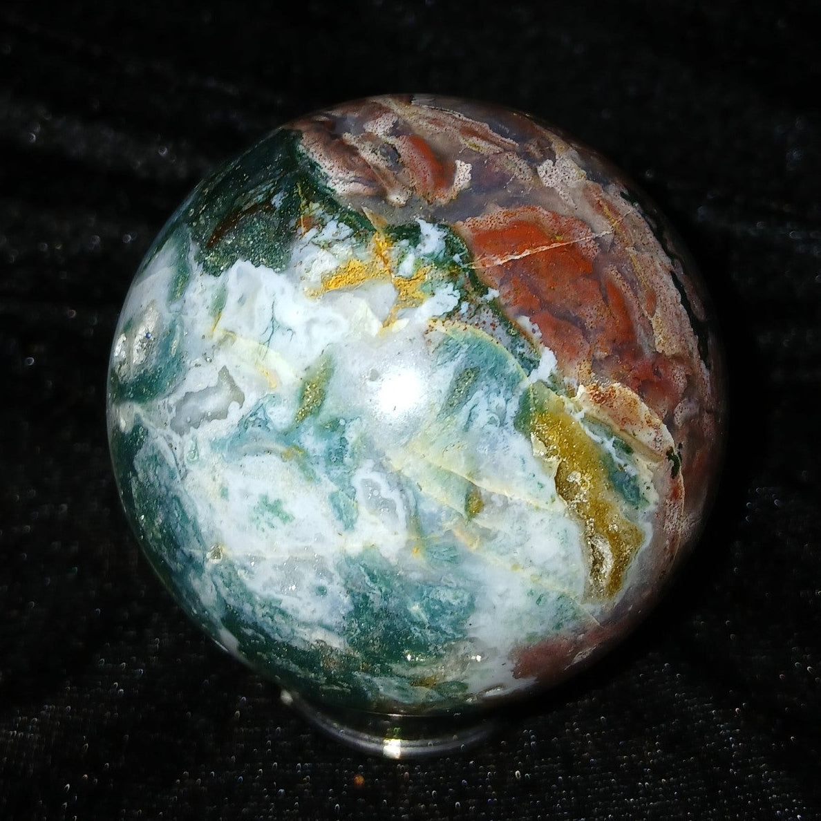Fordite Haus: Crystals & Fordite 57.4mm Ocean Jasper sphere from Madagascar with green, white, and red patterns.