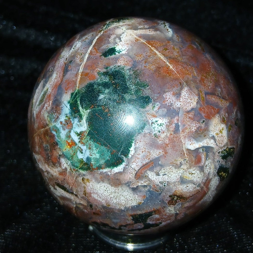 Fordite Haus: Crystals & Fordite 57.4mm Ocean Jasper sphere from Madagascar with green, red, and white patterns.