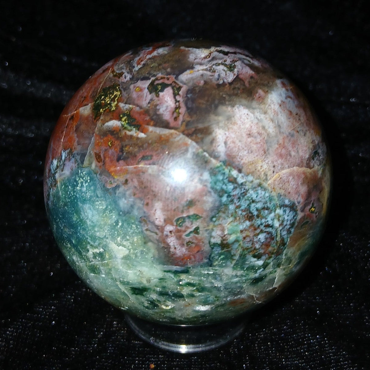Fordite Haus: Crystals & Fordite 57.3mm Ocean Jasper sphere featuring greenish blue, red, pink, and white patterns.