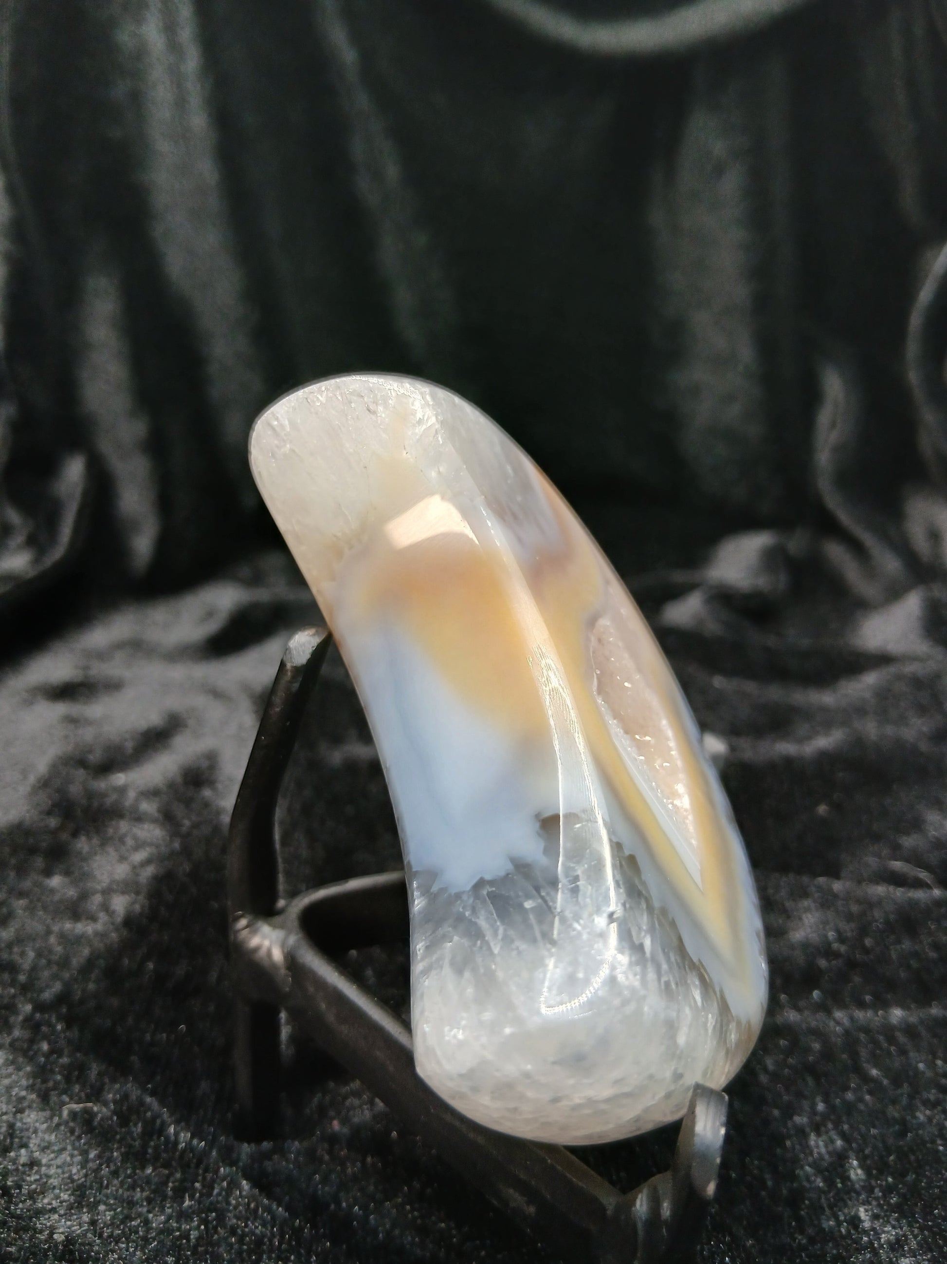 Fordite Haus: Crystals & Fordite polished peach and cream agate crescent moon carving on a black display stand.