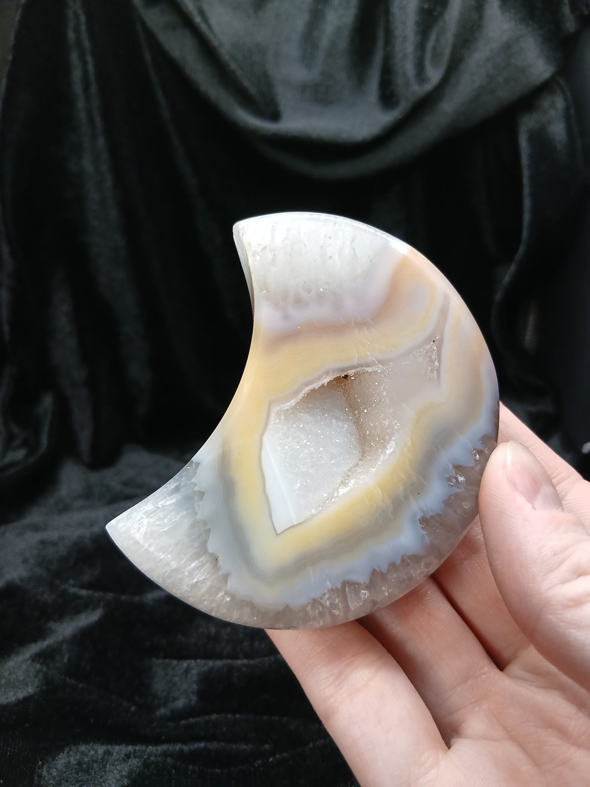 Fordite Haus: Crystals & Fordite peachy agate moon carving with natural cream banding and a central druzy geode center.