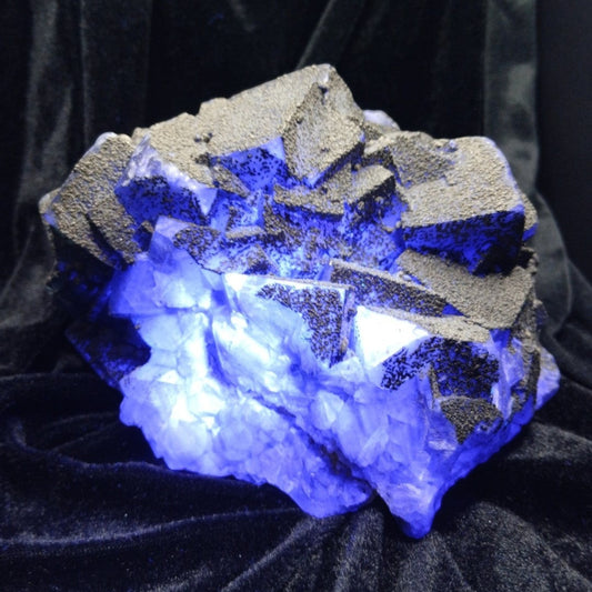Fordite Haus: Crystals & Fordite 6.9lb cubic fluorite mineral specimen with pyrite dusting glowing in blue light