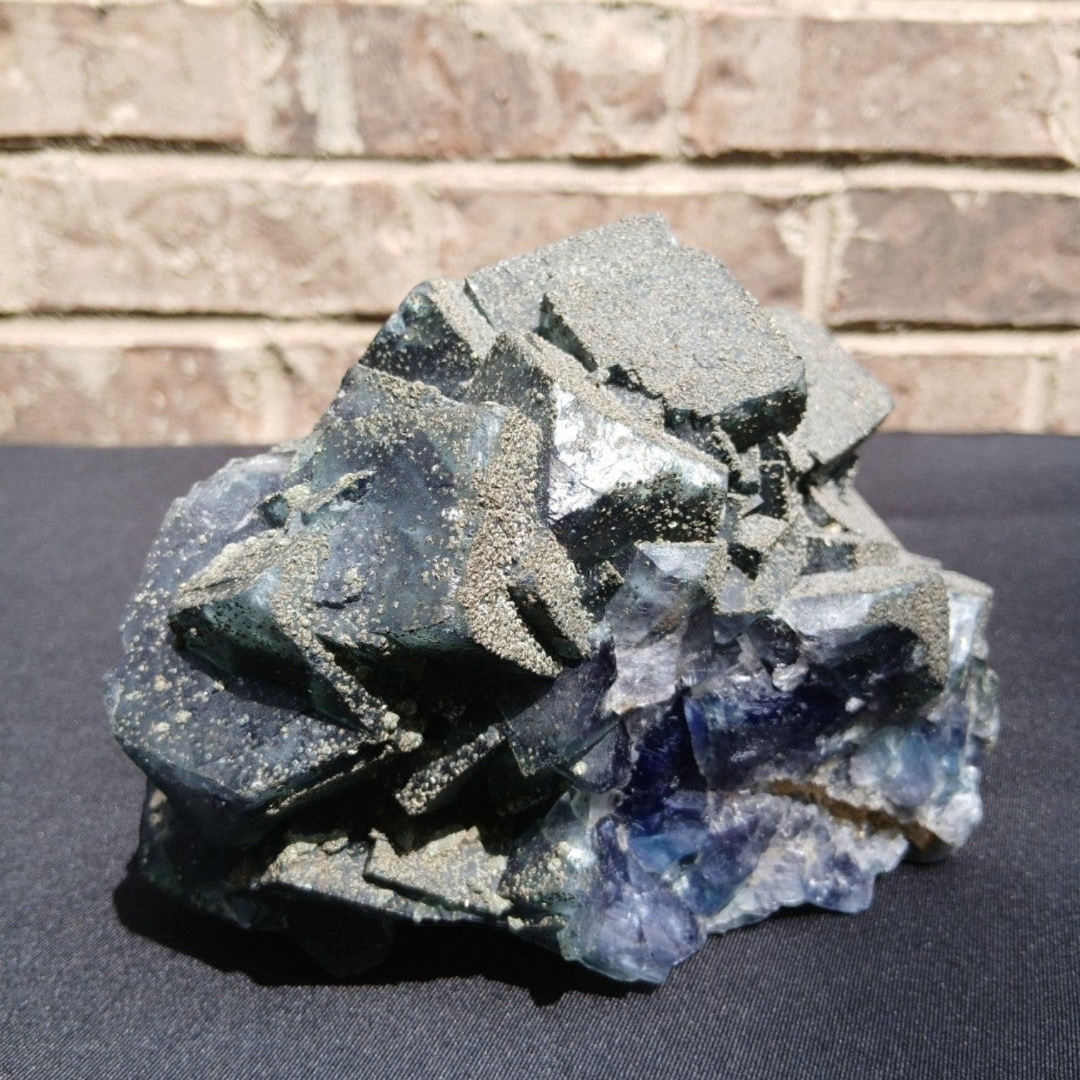 Fordite Haus: Crystals & Fordite 6.9lb cubic fluorite mineral specimen with green and blue tones and pyrite dusting.