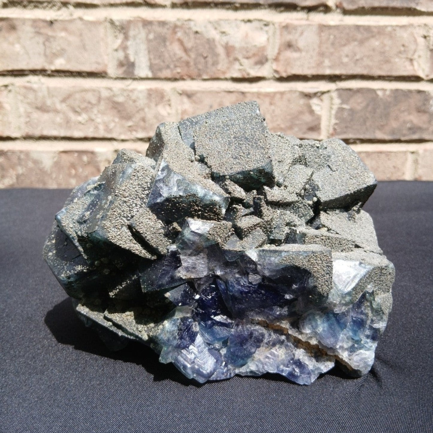 Fordite Haus: Crystals & Fordite 6.9lb cubic fluorite mineral specimen with green and blue tones and pyrite dusting.