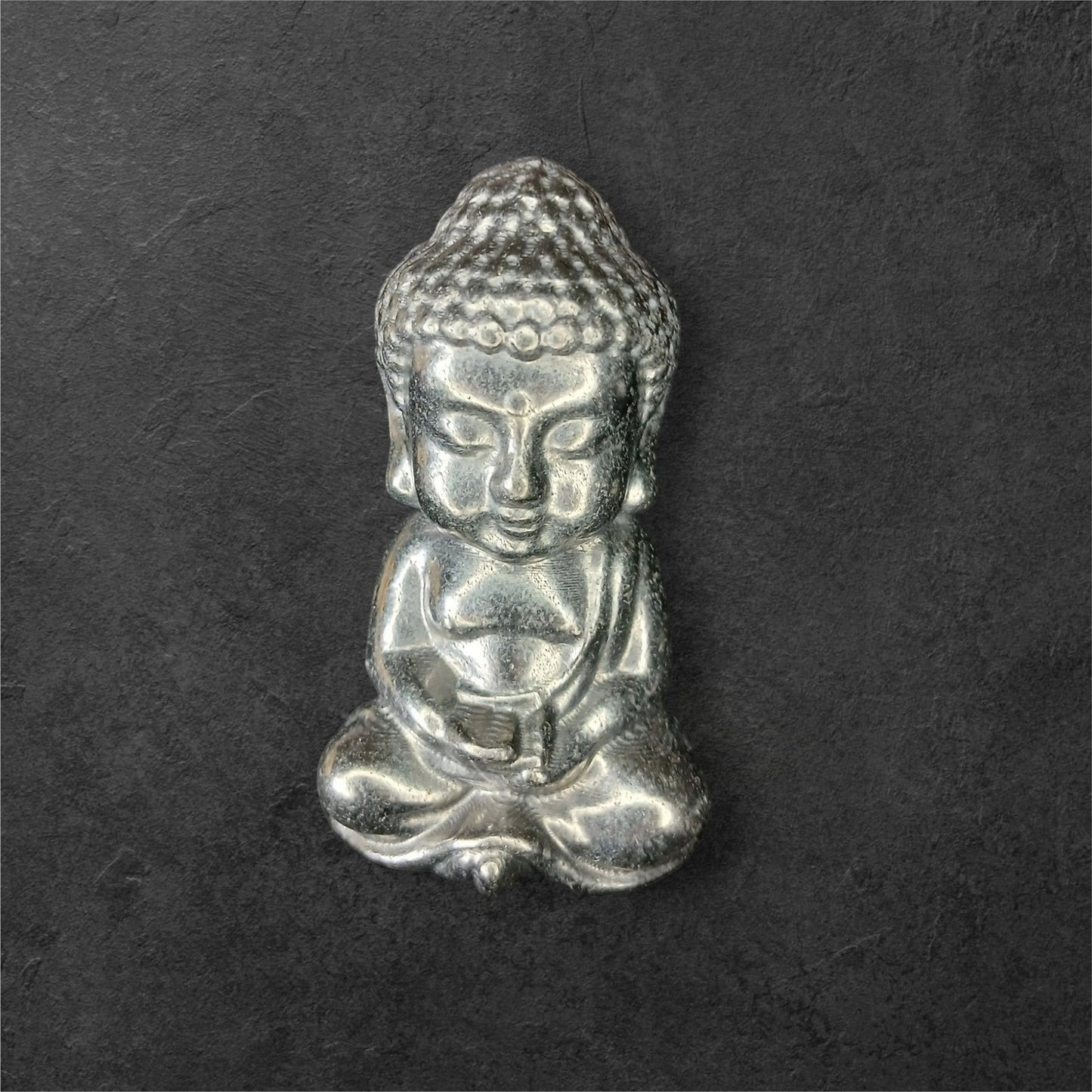 Fordite Haus: Crystals & Fordite small silver meditating Buddha figurine with intricate hair and serene expression.