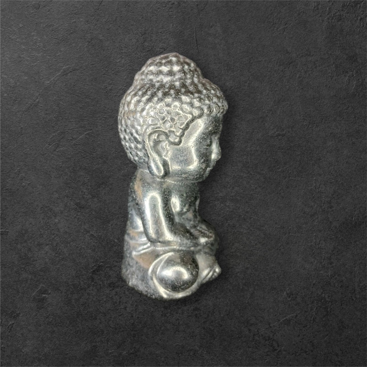 Fordite Haus: Crystals & Fordite small metallic silver meditating Buddha figurine in a seated pose.