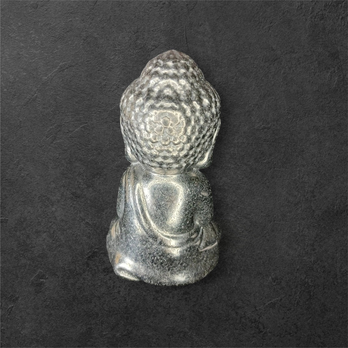 Fordite Haus: Crystals & Fordite small metallic silver meditating Buddha figurine viewed from the back.