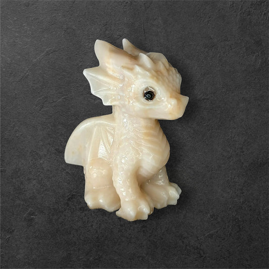 Fordite Haus: Crystals & Fordite light yellow calcite dragon figurine with smooth texture on a dark background.