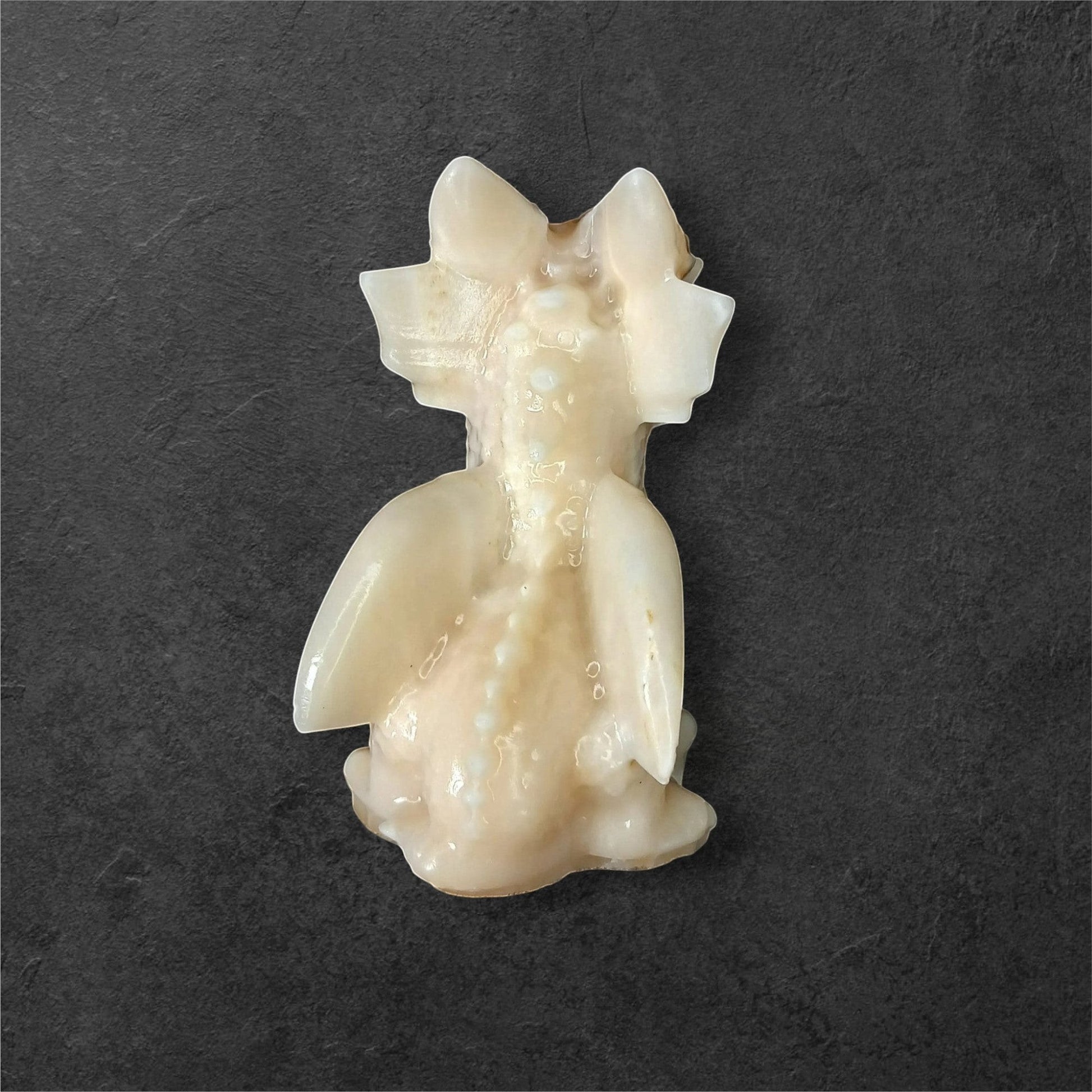 Fordite Haus: Crystals & Fordite light yellow calcite dragon figurine with smooth polished finish on dark background